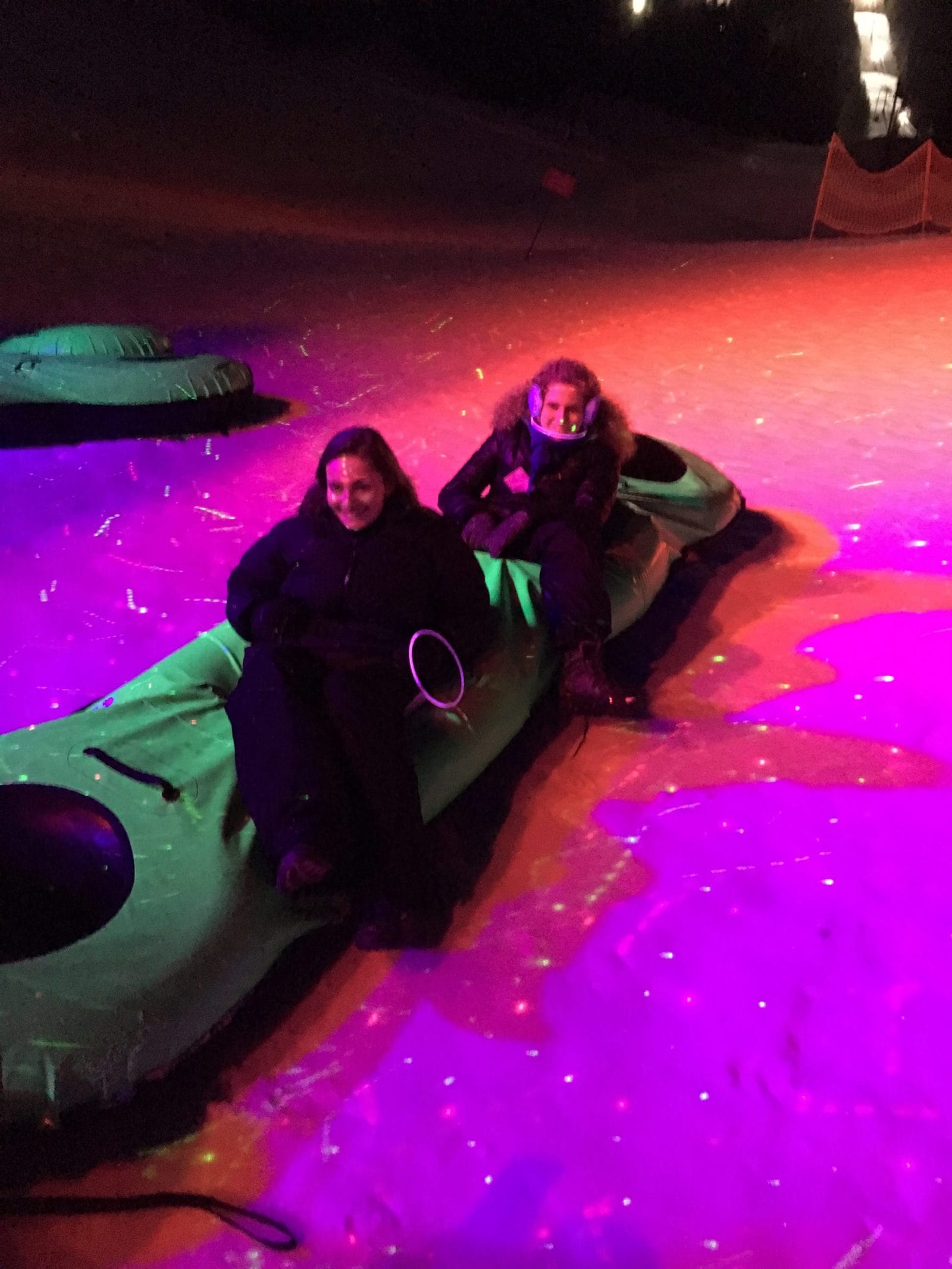 Ari and Lauren test out a multi-seater snow tube under the lights of "cosmic snow tubing".