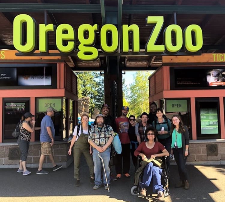 Aliza, left, with Street Roots vendors and staff at the entrance of the Oregon Zoo.